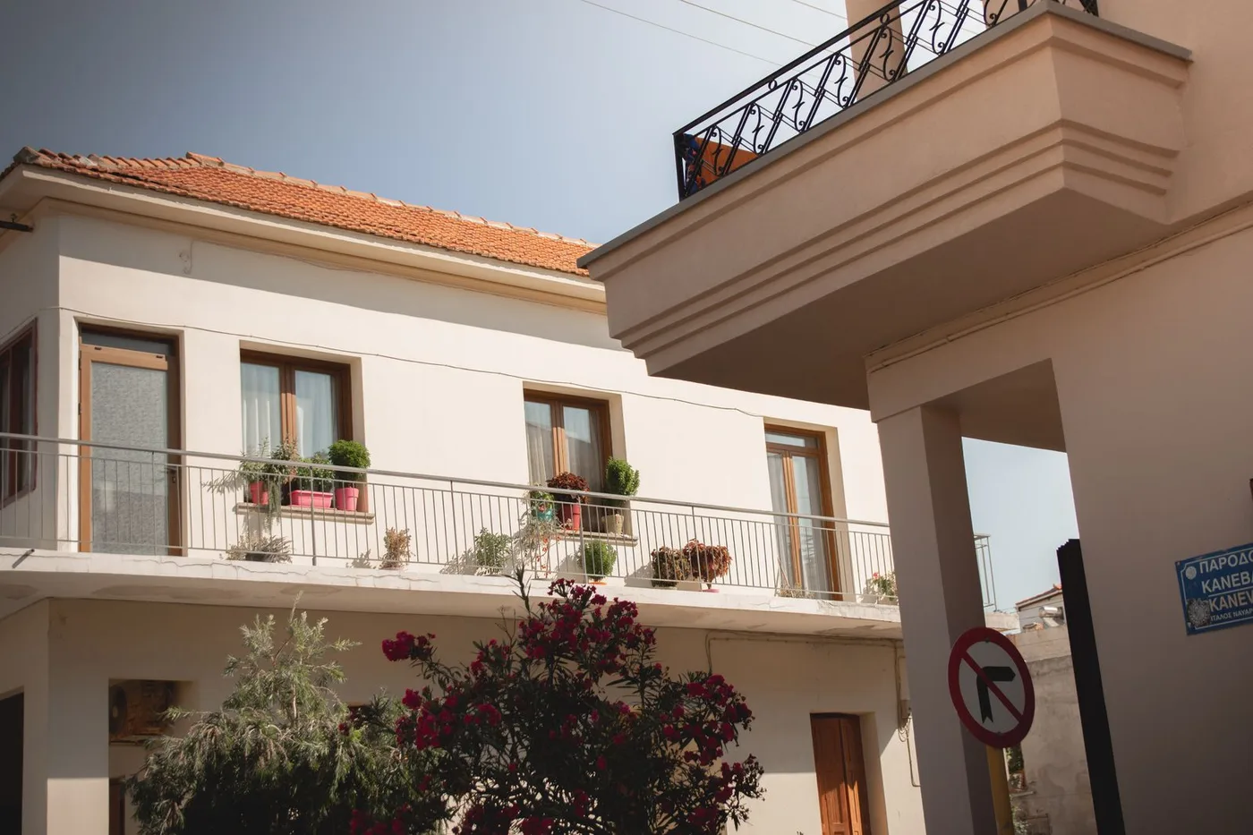 Façade d'une maison grecque traditionnelle avec un balcon et des plantes en pot